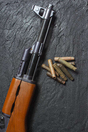 old rusty spent cartridges and a gun barrel on black concrete