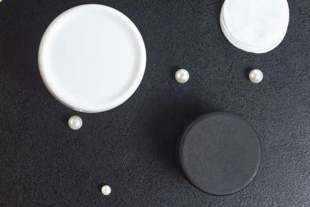 white and black jar cosmetic for bath cotton pearl disks on a black table. Copyspace. mockup. top...