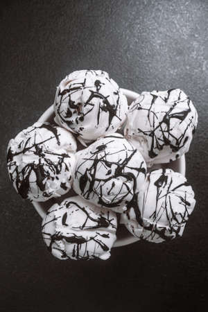 white ice-cream balls in a plate poured chocolate on a black table. close up, copy space. top view, flat layの写真素材