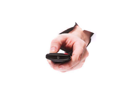 male hand with tv remote control through a hole in paper on a white background isolate. close up,...