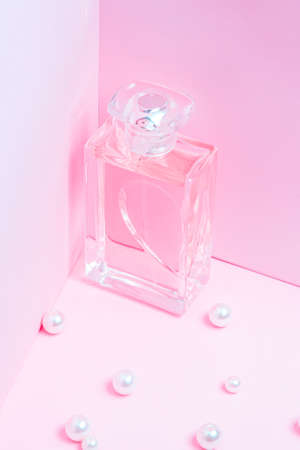 pink perfume bottle with pearls on a pink background copy space. bot view, vertical orientation, mock upの写真素材