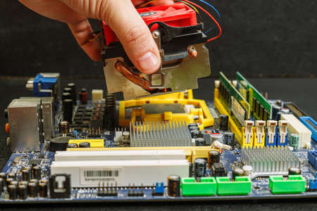 computer motherboard hand puts a cooler on the processor, on the table repair equipment