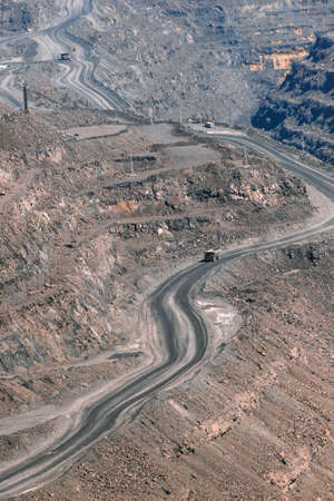 iron ore quarry dump truck moves on the road of stepped terraced terrain, mining industry, mining...
