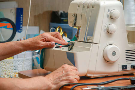 female old wrinkled hands sew on a sewing machineの写真素材