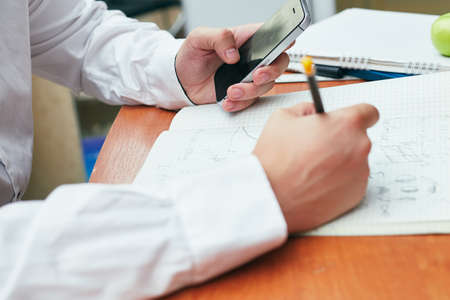a man in a white shirt writes in a notebook university, collegeの写真素材