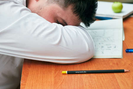 a man sleeping on a table with a notebook and a pencil university, collegeの写真素材
