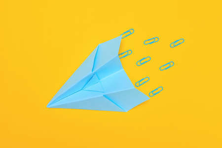Minimalism, blue paper airplane on yellow background, flat lay copy space