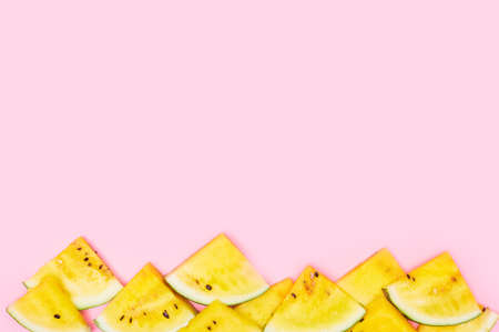 slices of yellow watermelon on a pastel pink background, copyspace, layout