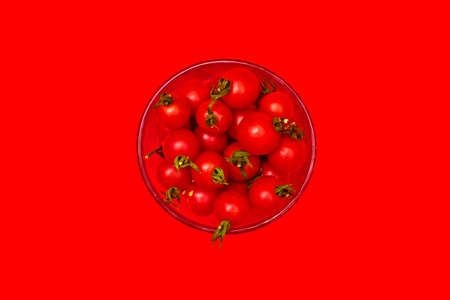 cherry tomatoes in a glass on a red background top view oneの写真素材