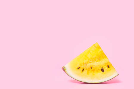 slices of yellow watermelon on a pastel pink background, copyspace