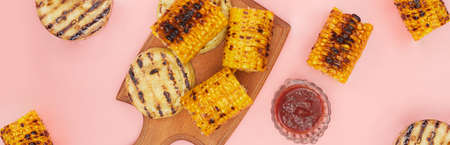 grilled vegetables corn on a pastel pink background, copies of space, flatlay