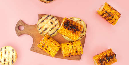 grilled vegetables corn on a pastel pink background, copies of space, flatlay