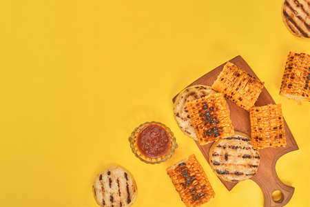 grilled corn vegetables on a yellow background, copy space, flatlay