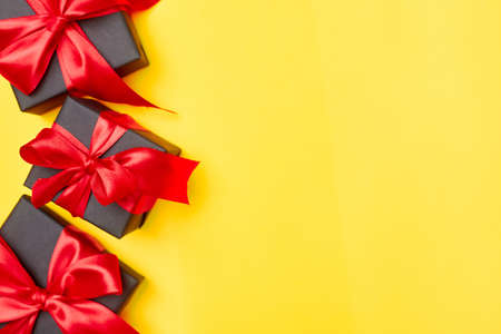 Black friday sale flat lay with gift box and ribbon, copy space, christmas and holidays concept on yellow backgroundの写真素材
