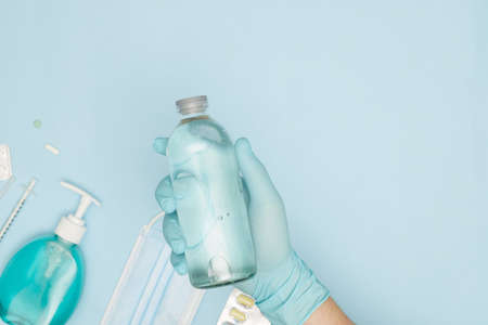 hand in glove with nat solution on blue background covid-19 coronavirus prevention concept flat lay