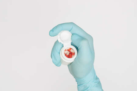 hand in glove with jar of capsules on white background covid-19 coronavirus prevention concept flat layの写真素材