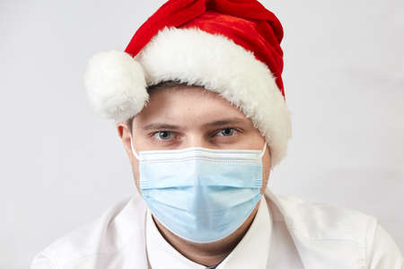 coronavirus concept, man in santa hat and medical mask on white backgroundの写真素材