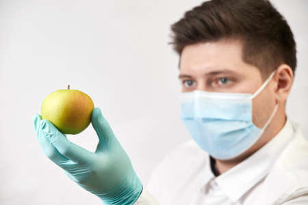 coronavirus concept, salesman with apple in gloves and mask on white backgroundの写真素材