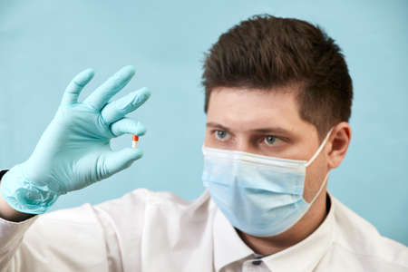 man in medical protective mask with pills on blue backgroundの写真素材