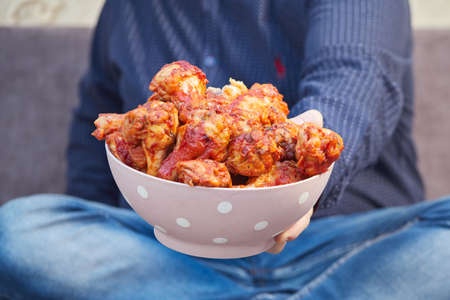 man on the couch with a plate of Buffalo Chicken Wings, copy spaceの写真素材