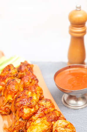 Buffalo chicken wings on a wooden board with celery on a concrete background, copy spaceの写真素材