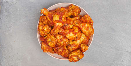 Buffalo chicken wings in a plate on a gray concrete background, copy spaceの写真素材