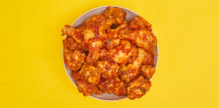 Buffalo chicken wings in a bowl on a yellow background, copy spaceの写真素材