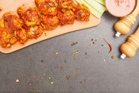 Buffalo chicken wings on a wooden board with celery, top view, copy spaceの写真素材