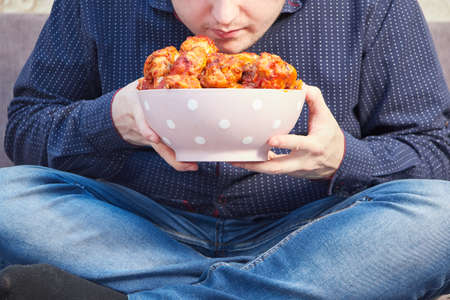 man on the couch with a plate of Buffalo Chicken Wings, copy spaceの写真素材