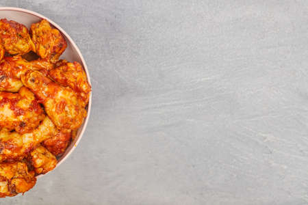 Buffalo chicken wings in a plate on a gray concrete background, copy spaceの写真素材