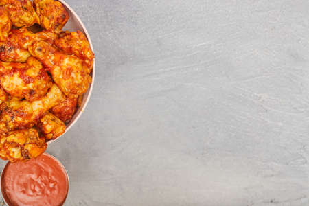 Buffalo chicken wings in a plate on a gray concrete background, copy spaceの写真素材