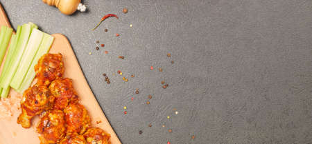 Buffalo chicken wings on a wooden board with celery, top view, copy spaceの写真素材