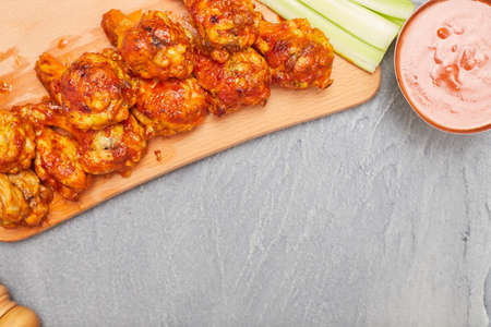 Buffalo chicken wings on a wooden board with celery on a concrete background, top view, copy spaceの写真素材