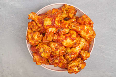 Buffalo chicken wings in a plate on a gray concrete background, copy spaceの写真素材