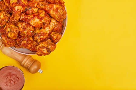 Buffalo chicken wings in a bowl on a yellow background, copy spaceの写真素材