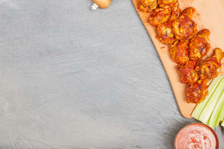 Buffalo chicken wings on a wooden board with celery on a concrete background, top view, copy spaceの写真素材