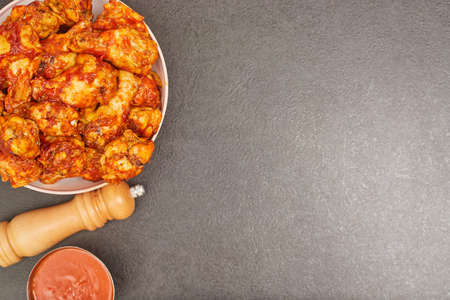 Buffalo chicken wings in a plate on a black table background, copy spaceの写真素材
