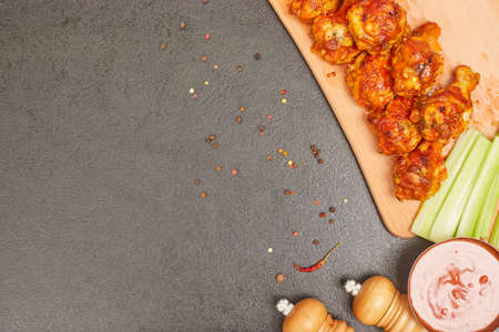 Buffalo chicken wings on a wooden board with celery, top view, copy spaceの写真素材