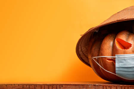 halloween pumpkins in a medical mask on an orange background copy spaceの写真素材