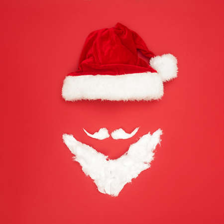 Christmas concert, Christmas hat and beard on a red background, top view, copy spaceの写真素材