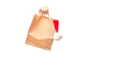 hand holds craft bag with santa hat on white background isolate, banner, copy space