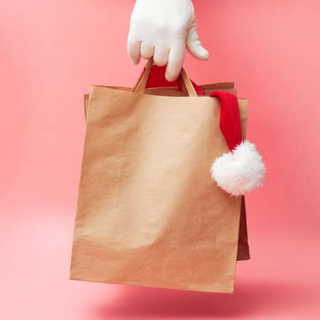 christmas concept, two paper bags in hand, discounts on clothes and accessories, on pink background, banner, copy space, mock upの写真素材