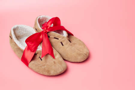 winter slippers with fur in a red ribbon, on a blue background, banner, copy space, mock upの写真素材