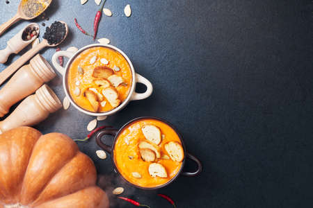 pumpkin cream soup with croutons on a black table with spicesの写真素材