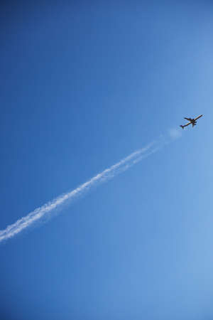 an airplane in a clear sky takes off leaving a line, vertical orientationの写真素材