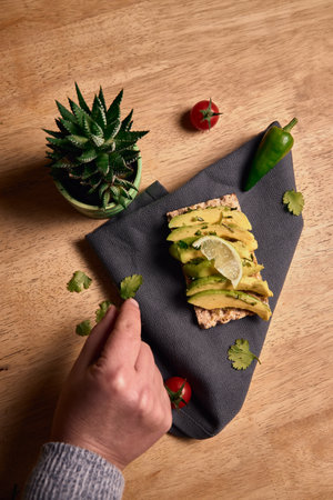 healthy vegan breakfast. avocado toast with lime and coriander on top of a dark napkin on a wooden...