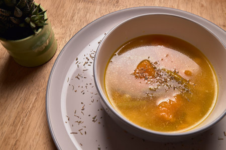 Vegetable soup or broth with pumpkin and chickpeas in a bowl. fine spreading herbs. solid wood background. Healthy, vegan and diet foodの写真素材