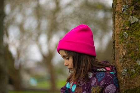 close-up Caucasian girl standing up With casual clothes and a pink hat. In a natural park.の写真素材