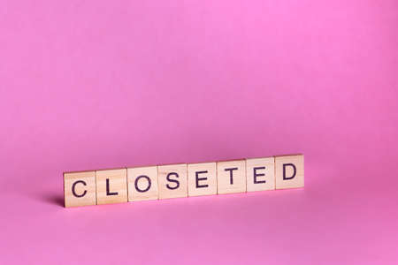 Closeted words represented by wooden letter tiles isolated on color background with copy space. LGBTQ, LGBTQQIA concept.の写真素材