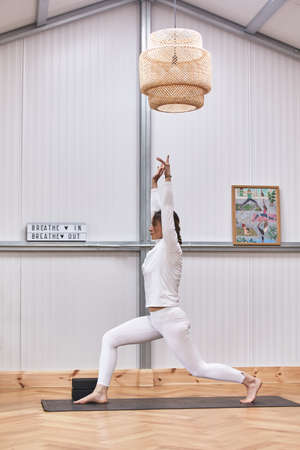 warrior's posture on a blonde Caucasian woman inside a beautifully decorated gymの写真素材
